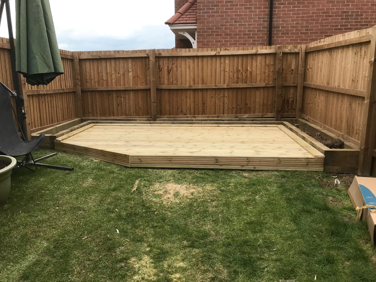 An image of decking in a garden next to a fence.